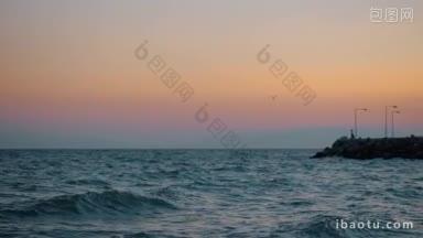 用慢动作拍摄了海浪的岩石码头和孤独的海鸥在夜空中飞翔